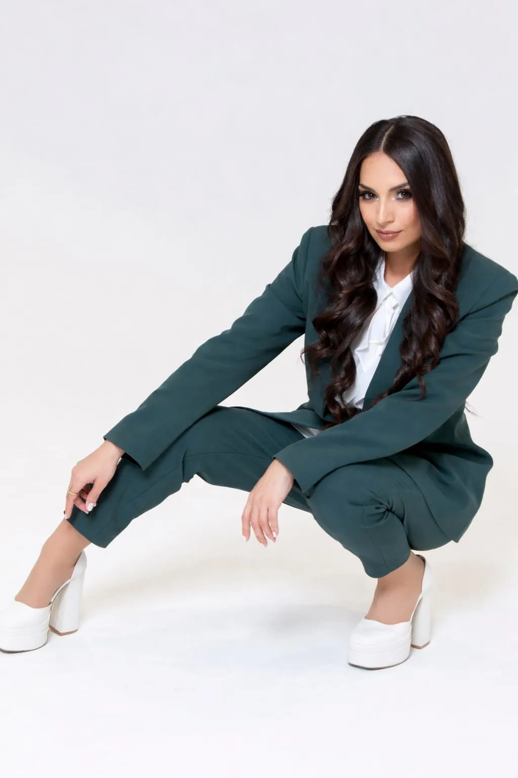 Ghazaleh Ghasemi editorial portrait, Persian-Canadian motivational speaker and event producer, crouching pose in tailored suit
