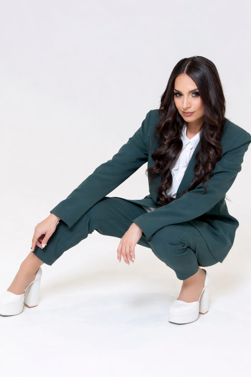 Ghazaleh Ghasemi crouching in a tailored suit, editorial fashion portrait for Your Soul Sister keynote speaker brand