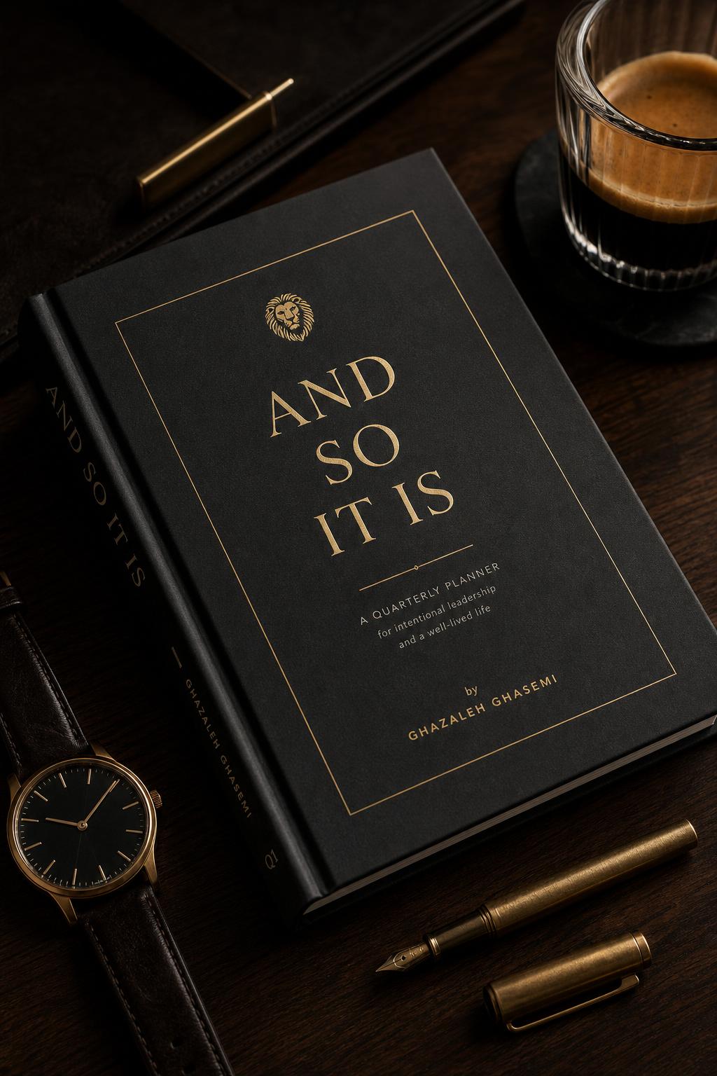 Masculine Edition of And So It Is neurodivergent quarterly goal planner by Ghazaleh Ghasemi — graphite, ink and brushed-gold cover on a dark leather desk with a brass pen and watch.