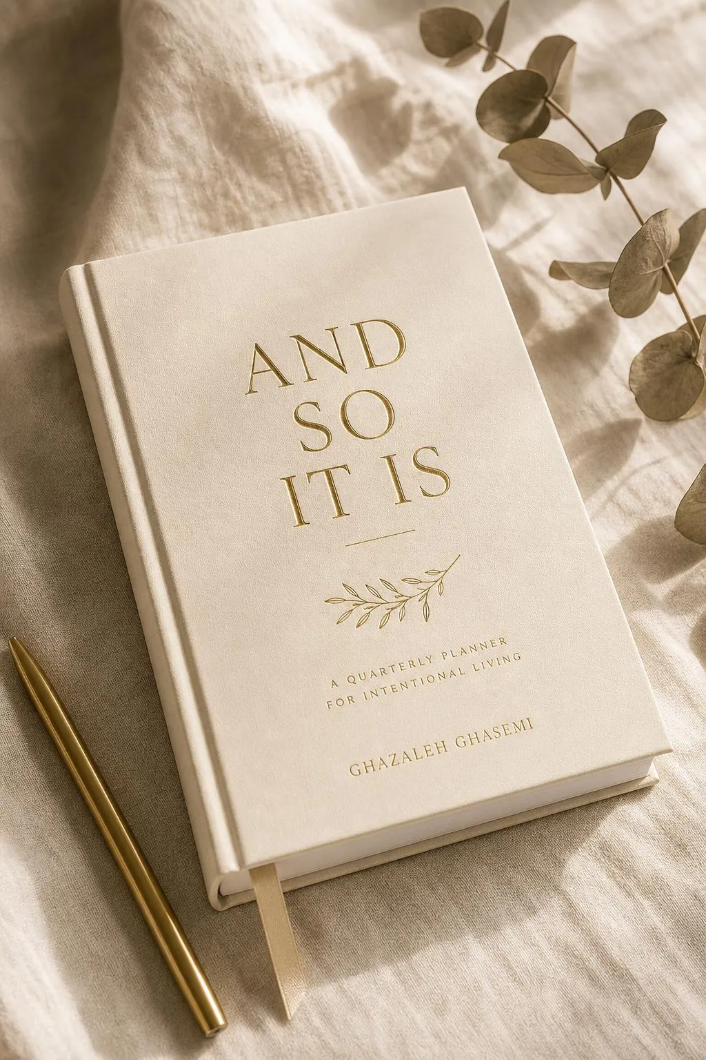 Neutral Edition of And So It Is quarterly goal planner for neurodivergent minds by Ghazaleh Ghasemi — bone, ink and gold-leaf cover styled with dried botanicals on a dark walnut table.